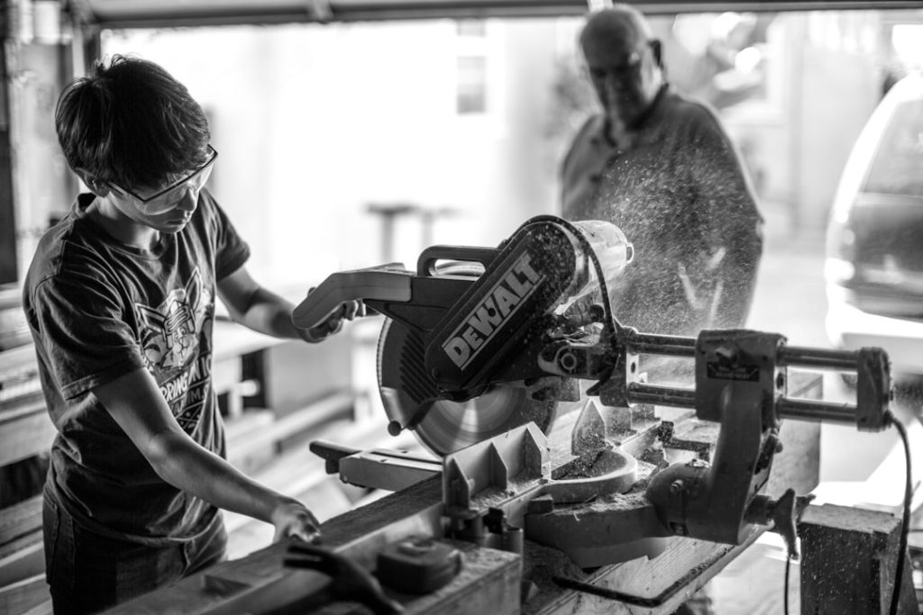 grayscale-photography-of-boy-using-miter-saw-38oohn-r6aa