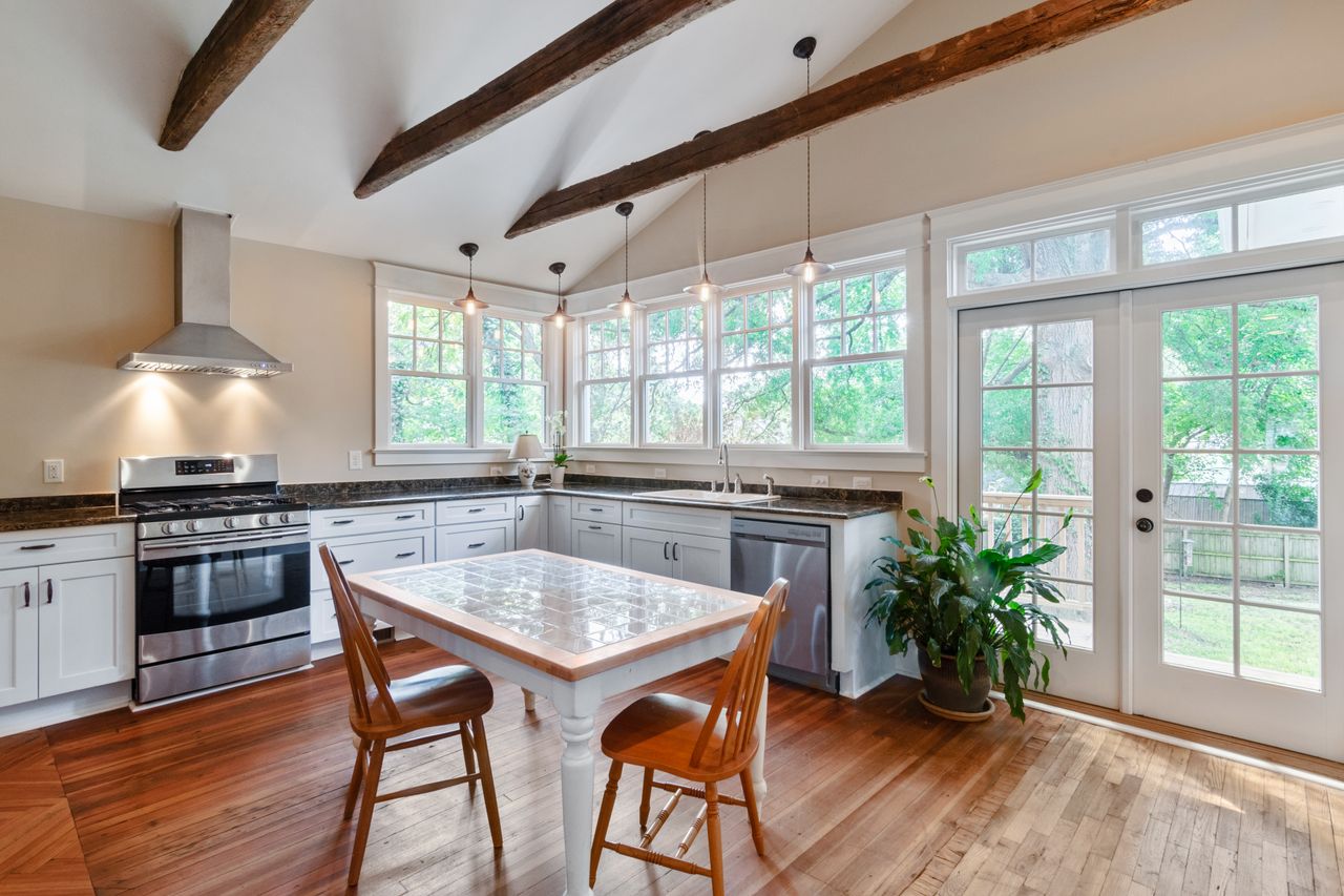 Bright rustic kitchen with wooden beams, modern appliances, and garden view.